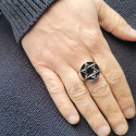 Primo piano dell'anello stella di David trasportato da un uomo che evidenzia il gioco leggero su acciaio lucido e lo sfondo nero