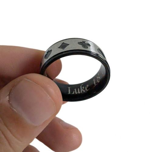 Primer plano de la mano llevó el anillo de un hombre, destacando la banda de plata y la chapa negra bajo la luz
