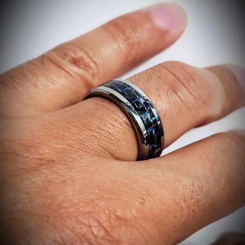 Demonstration of bluish reflections of carbon fiber and beveled edges of the ring on a male hand.