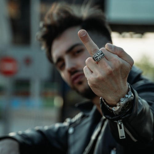 Homme au look rebelle et biker portant la chevalière en acier avec l'inscription provocatrice inversée