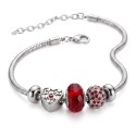 Vue détaillée des ravissantes breloques montrant la perle rouge brillante et la sphère incrustée de cristaux scintillants