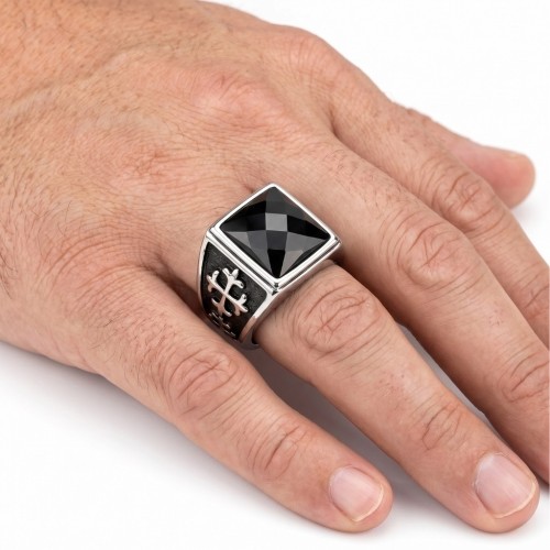Gros plan de la bague portée à la main d'un homme, mettant en valeur les reflets de la pierre carrée facettée sous la lumière