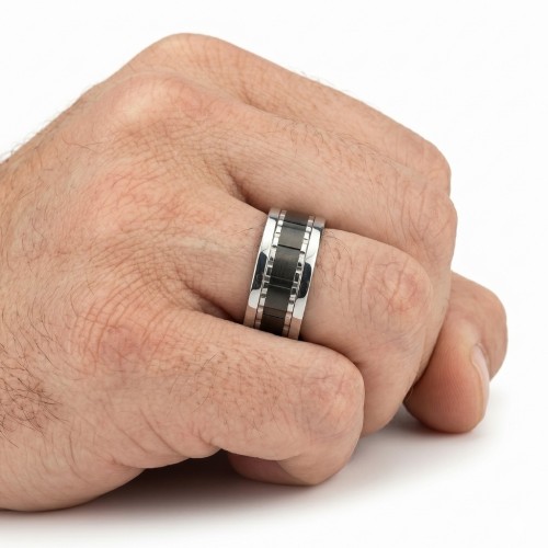 Vista de la mano llevada con un anillo de un hombre, destacando el contraste de la banda negra anotada bajo luz