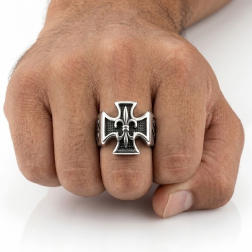 Close-up of the hand carried ring of a man, highlighting the brilliance of the lily flower contrasting with the blackened backgr