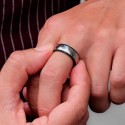 Anello titanio tritato indossato all'annular di un uomo per simboleggiare un matrimonio o un impegno con uno stile moderno