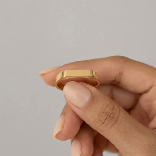 Rectangular knight in golden stainless steel shown by a woman for an urban style, minimalist and modern