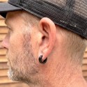 Boucles d'oreilles anneaux noirs portées à l'oreille par un homme au style moderne et contemporain