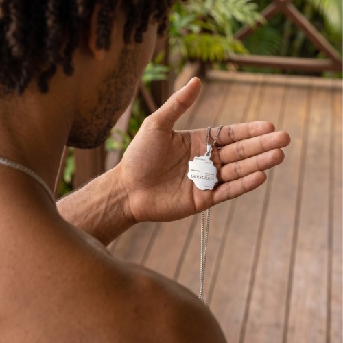Détail du pendentif carte Île de la Réunion en acier tenu en main, un bijou symbolique pour homme.