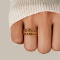 Anello regolabile in acciaio dorato con motivo openwork di foglie di alloro e bordi perline, guidati da una donna.
