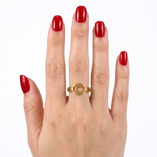 Bague ouverte ajustable en acier inoxydable doré ajourée avec initiale lettre C au centre portée par une femme.