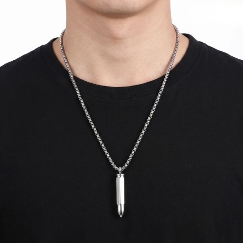 Chaine et pendentif balle de revolver porté par un homme, soulignant son style brut et décontracté.