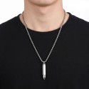 Ciondolo a sfera a catena e revolver indossato da un uomo, evidenziando il suo stile crudo e casual.