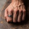 Gros plan sur la bague anti-stress noire à motif damier portée sur le poing d'un homme au style moderne.