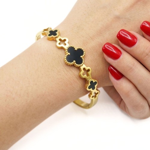 Femme portant un bracelet jonc rigide en acier inoxydable doré, orné de plusieurs trèfles pour un style original et moderne