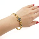 Bracelet jonc rigide pour femme en acier inoxydable doré, orné d'un trèfle central noir et de petits trèfles ajourés.