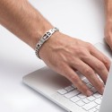 Man working on a laptop while wearing his cubaine mesh gourmette adorned with the Latin cross.
