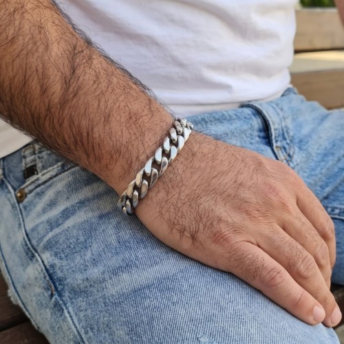 Armband, das von einem Mann in kubanem Edelstahl von 12 mm Breite mit Karabinerschließe getragen wird.