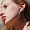 Schließen Sie oben auf dem Profil einer Frau, die das Volumen hervorhebt, und Glanz des Stahlwasser-Tropfenohrs.