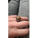 Anello con sigillo tribale in acciaio color argento e occhio di tigre indossato da un uomo