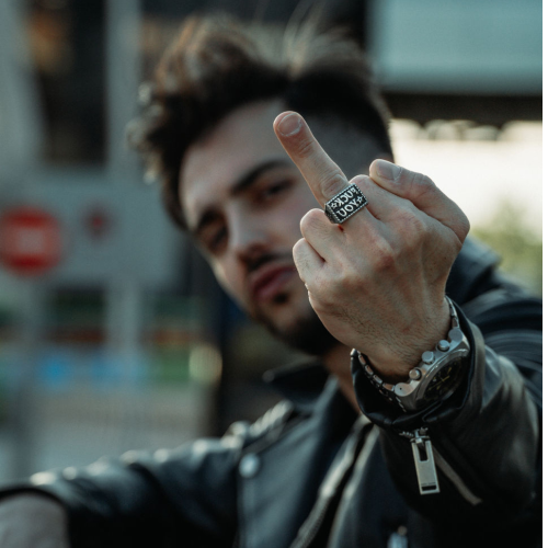 Siegelring aus Stahl mit einem Fuck You-Stern mit eingraviertem Biker-Rebell, der von einem Mann am Mittelfinger getragen wird