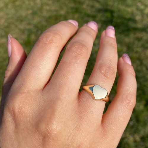 Anello con sigillo in acciaio dorato a forma di cuore in oro fine indossato da una donna