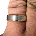 Golden engagement ring and brushed steel band worn by a man