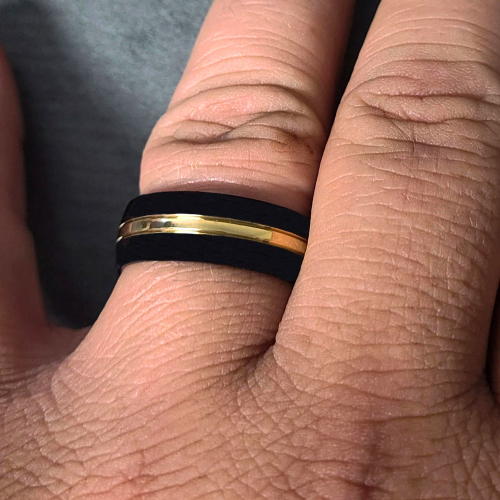 Anello di fidanzamento in titanio nero bicolore con fascia in oro indossato da un uomo