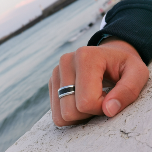 Anillo de acero inoxidable y banda de fibra de carbono negra usado por un hombre