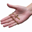Collar de hombre con colgante de cruz ankh egipcia de acero dorado en una mano