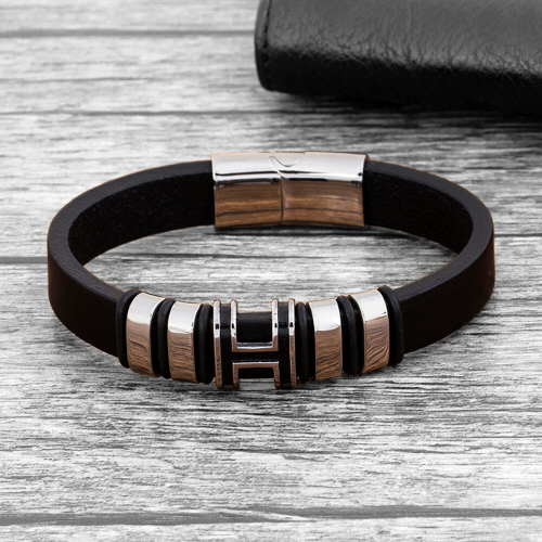 Pulsera de hombre en cuero negro y cilindros letra H con cierre magnético de acero sobre una mesa