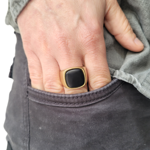 Anello di deglutizione in acciaio dorato unico set con un onice nero indossato da un uomo