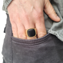 Anillo de cinta de acero de oro conjunto con un ónix negro usado por un hombre