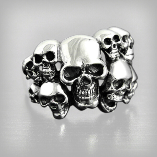 BIKER knit ring for man made of stainless steel carved with multiple death heads on a blackened background.