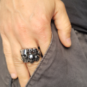 Man carrying a biker ring with steel skulls, highlighting the openwork structure of the ring.